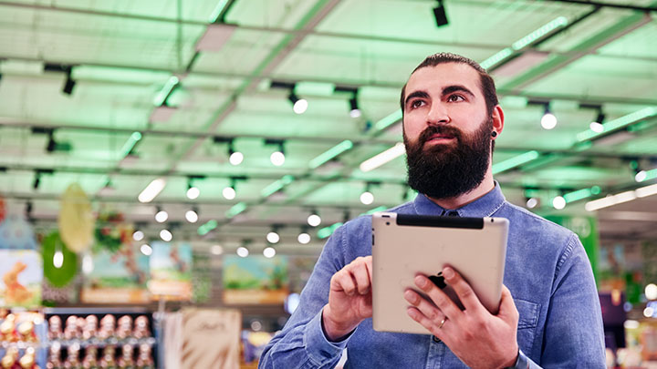 Un homme contr&ocirc;lant l'environnement de son magasin via une tablette