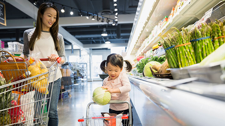 Jeune fille achetant des l&eacute;gumes avec sa m&egrave;re
