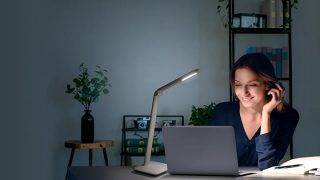 "Niño estudiando en el escritorio con una luminaria de trabajo LED ajustable, que proporciona una iluminación óptima para hacer los deberes en un colorido espacio de aprendizaje en casa".