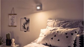"Elegante dormitorio con foco de luz concentrada LED regulable que crea un ambiente acogedor, iluminando la ropa de cama geométrica y la decoración minimalista".