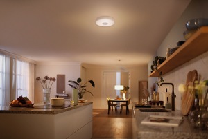 Een grote keuken wordt verlicht met gedimd licht door plafondverlichting en een hanglamp