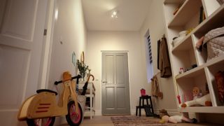 "Heldere entree met LED inbouwspots die planken, speelgoed en een loopfiets voor kinderen verlicht."