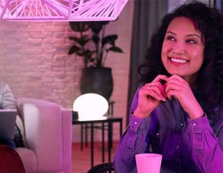 "Levendige roze LED hanglamp en slimme tafellamp creëren speelse sfeer, verlichten de verrukte expressie van de vrouw in de moderne leefruimte"