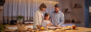Una madre y un padre se paran con su hija en una cocina bien iluminada