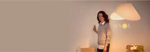 "Woman adjusting smart dimmer switch, controlling warm LED lighting ambiance in contemporary living space with minimalist decor"