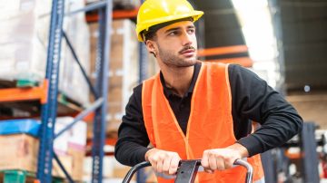 Man with construction hat pushing dolly