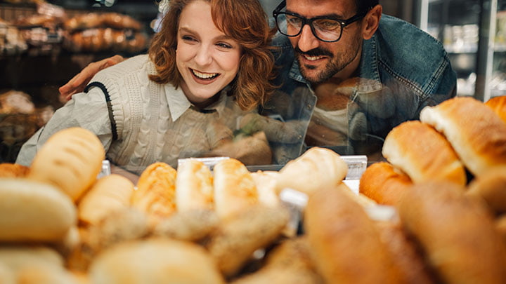 Person smiling behind a bakery counter with bread