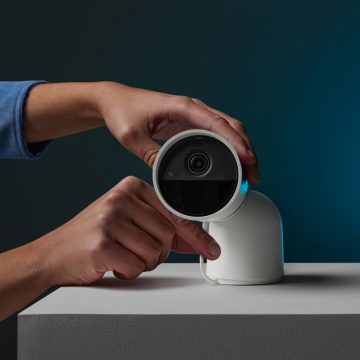 Manos ajustando una cámara Secure blanca con soporte de escritorio