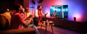 A group of friends celebrate a goal seen on a TV football match with the Hue Sports Live feature making lights react to the moment in tones of pink and blue.