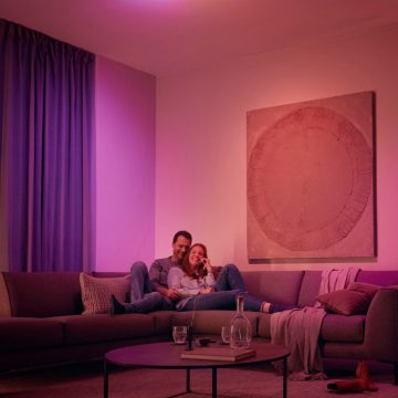 Un couple se détendant sur un canapé entouré d'une douce lumière rose et violette.