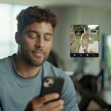 Een man ziet een bezorger bij de voordeur via de Hue app op zijn smartphone.