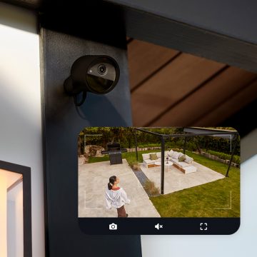 A Hue Secure camera attached to a wall and a live image from the camera showing a woman in a backyard.