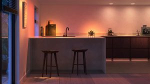 Modern kitchen interior with soft ambient lighting illuminating countertops, bar stools, and wall, creating a warm evening atmosphere.