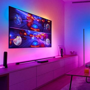 Un juego de carreras aparece en una gran pantalla de televisión colgada en una pared con Iluminación envolvente sincronizada a su alrededor.