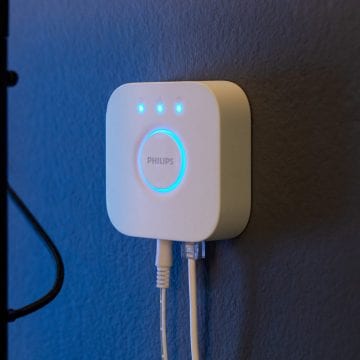 El dispositivo Hue Bridge cuelga de una pared de color azul.