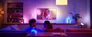 Man and woman seated on couch in front of LG TV with purple and blue Hue lighting