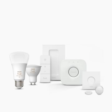 A set of smart lighting products including bulbs, sensors, a remote, and a hub, all in a white finish, displayed on a white background.