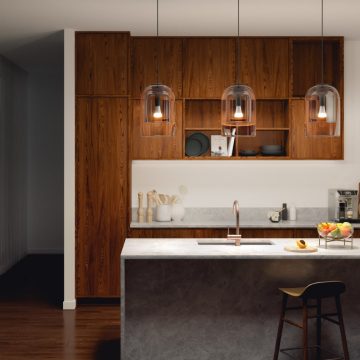 A group of pendant lights with clear glass shades is suspended above a kitchen island, casting focused light on the countertop.