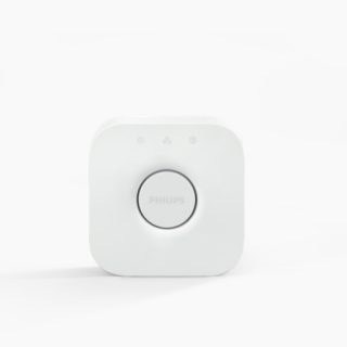 White square-shaped smart bridge device with rounded edges, matte finish, central circular button, and three small indicator icons above.