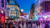 Night-time city street with colored lighting and pedestrians