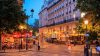 Night-time city street with colored lighting and pedestrians