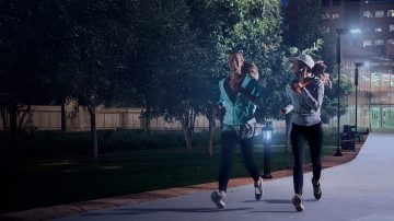 Gente corriendo de noche en un parque iluminado 