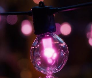 A Philips Hue Festavia outdoor globe string light glowing in pink. 