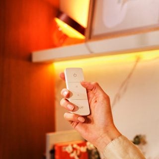 A hand holding a remote control to dim their lights.