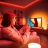A woman gaming on her TV with an immersive entertainment lighting setup glowing in red, orange, and white smart light. 
