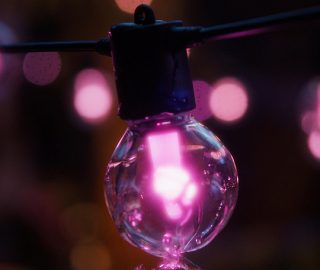 A Philips Hue Festavia outdoor globe string light glowing in pink. 