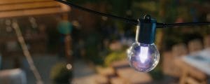 A Lightguide bulb on a string of Festavia outdoor globe lights shining in a light pink tone of light. 