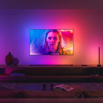 A TV synced with Philips Hue surround lighting glows in blue, pink, and red tones of light matching the on-screen image.