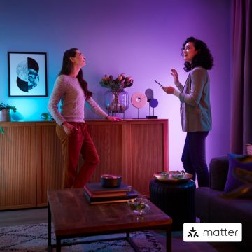 Two women standing in living room with colourful smart light