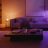 A sofa and coffee table stand in a room where the walls are lit with colorful accent lighting.