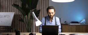 Person working with a study desk lamp in a modern study setting. 