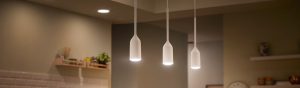 A collection of white pendant smart lights suspended above a kitchen area, emitting focused downward illumination onto the surface below.