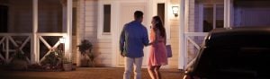 Two people approach a house entrance at night, illuminated by outdoor wall lights supporting visibility and security.