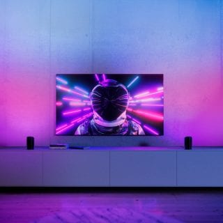 Two play wall washer lights placed each side of TV and glowing in vibrant pink and blue smart light.