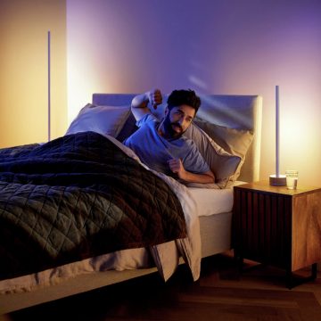 Person waking up in bed in a softly lit bedroom, with warm and cool smart lights enhancing the morning routine.