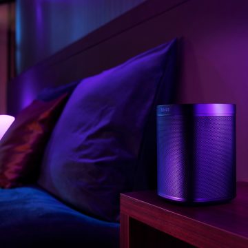 A living room scene with a speaker on a wooden table, illuminated by purple smart led strip lights creating a soft ambient glow.