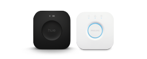 A set of two smart lighting hubs in black and white, both with circular central buttons and LED indicator lights.
