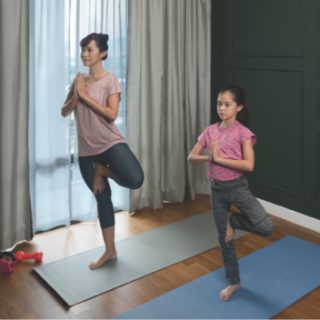 Two people practicing yoga on mats in a living room with natural light and recessed can lights illuminating the space.