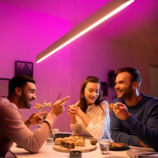 Group sharing a meal at a dining table under a smart pendant light with adjustable pink and white wireless lighting.