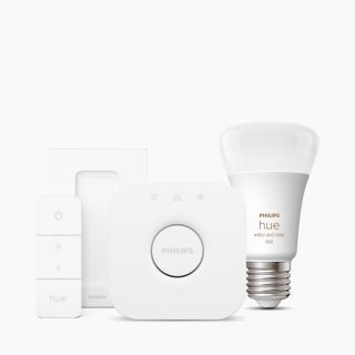 A collection of white smart lighting components including a bulb labeled ""hue white and color 800,"" a bridge, and a remote.