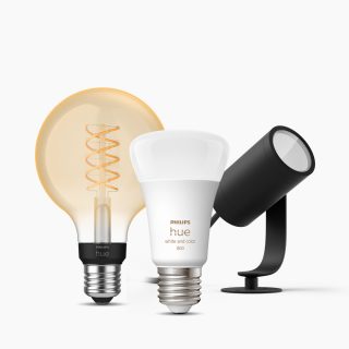 A collection of smart lighting products including a filament bulb, a white bulb, and a black spotlight lamp on a plain background.