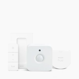 Collection of white smart lighting accessories including a remote control, wall mount, motion sensor, and module with visible text ""hue"".