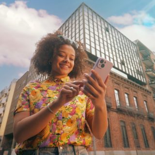 Una mujer sonriente comprueba el sistema de seguridad para el hogar inteligente en su smartphone 