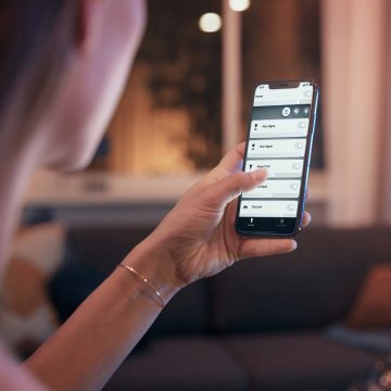 Mujer sosteniendo un teléfono que muestra una aplicación de luz inteligente