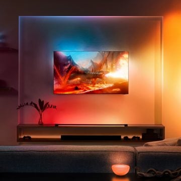 Téléviseur Samsung accroché au mur dans le salon entouré d'un jeu de lumières colorées 