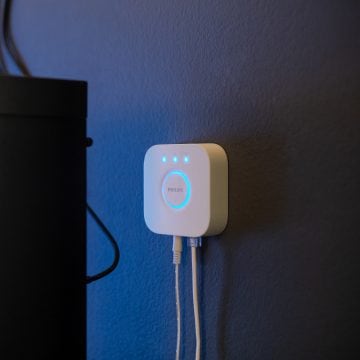 Philips Hue Bridge con cavi acceso e appeso a una parete